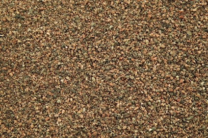 Närbild av en yta täckt med små bruna och beige stenar i olika nyanser.