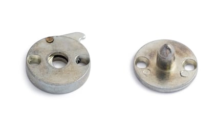 Två runda metalldelar, en med tre hål och krok, den andra med en centralt placerad tapp.