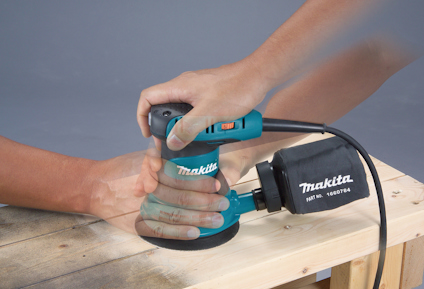 En person använder en Makita excenterslip på en träyta.